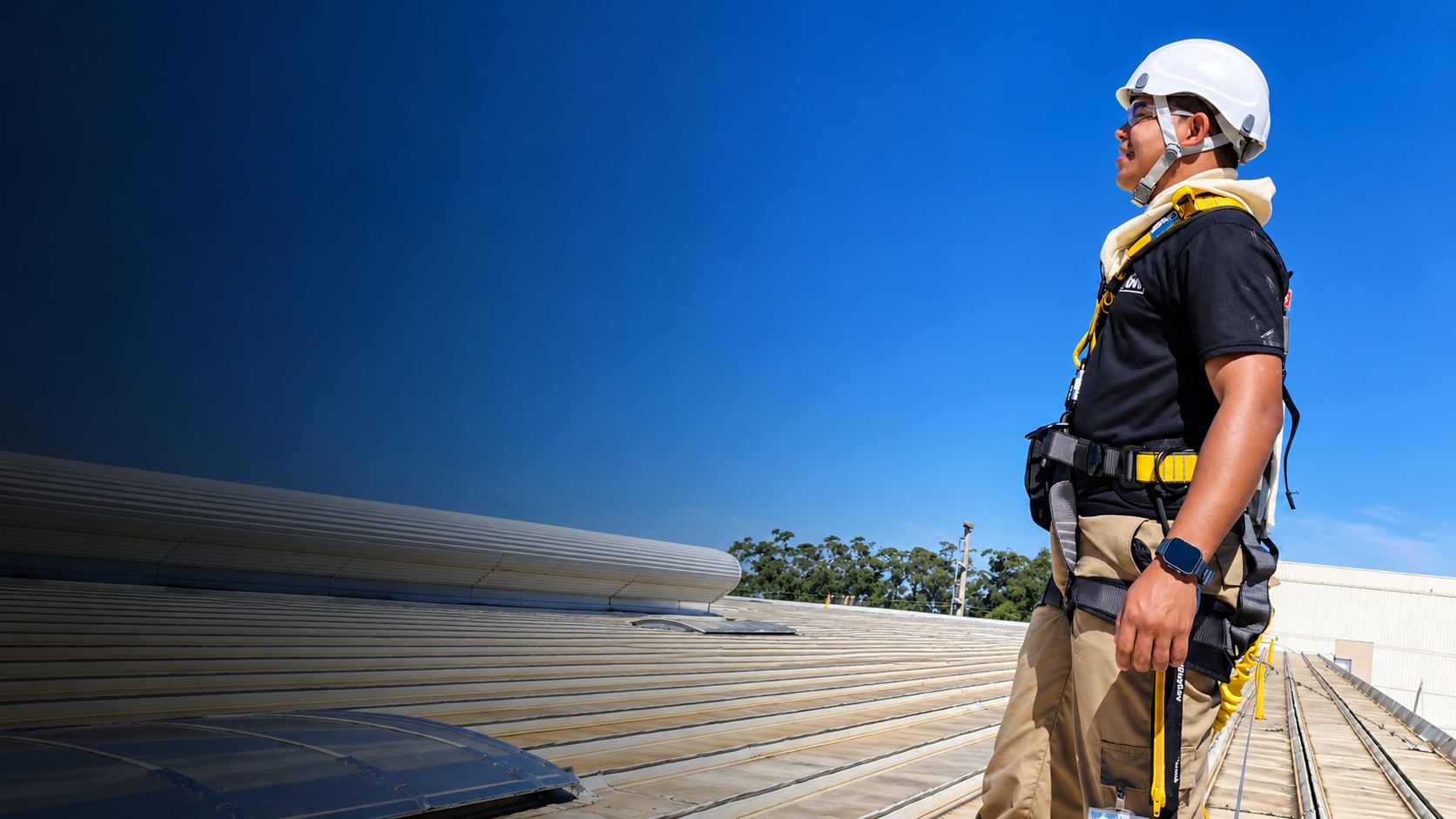 Profissional com capacete e cinto de segurança em telhado industrial